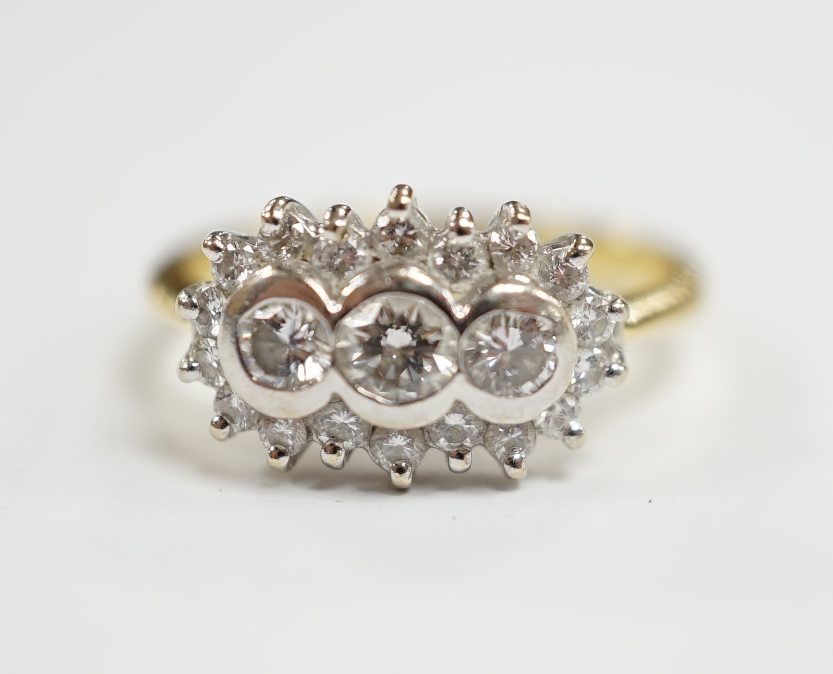 A modern 18ct gold and collet set three stone diamond ring, with diamond chip set border, size J/K, gross weight 4.6 grams.